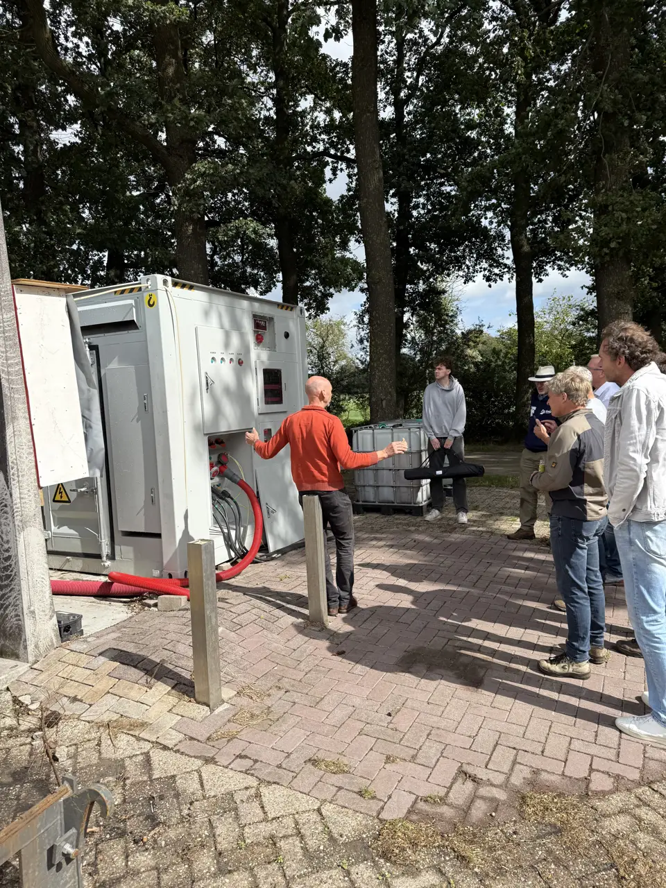 Een medewerker geeft bij de geopende container van de Vrije Netaansluiting uitleg aan een groep bezoekers